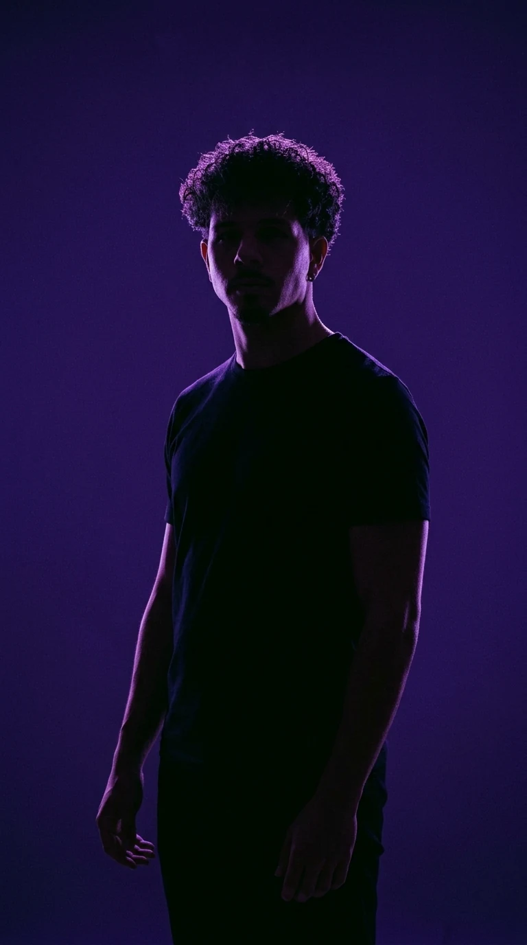 Marco Merlina in t-shirt nera, in controluce su fondo viola, sguardo di lato